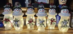 lighted snowmen with hats and wreaths on their heads are standing next to each other