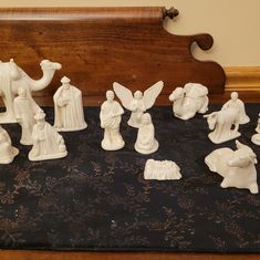 a group of figurines sitting on top of a black cloth covered table next to a wooden headboard