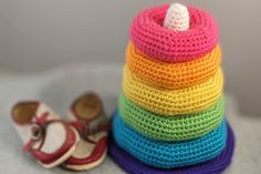 a stack of crocheted shoes next to a rainbow - colored yarn spool