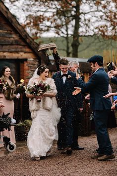 a bride and groom walking through confetti thrown by guests