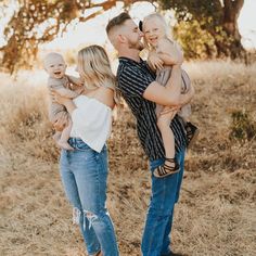 a man and woman are holding two babys in their arms while they look at each other