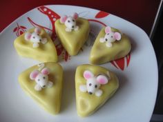 four pieces of cake on a white plate with red and red designs around it, including mouses