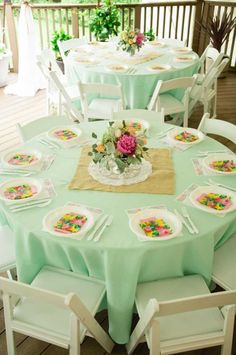 a table set up with plates and flowers on it for an outdoor dinner party or celebration