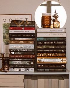 a stack of books sitting on top of a table next to a mirror and lamp