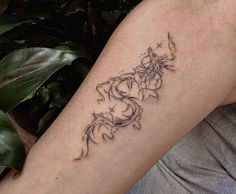 a woman's arm with a tattoo on it and a plant in the background