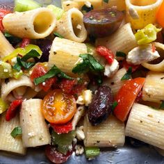 pasta salad with tomatoes, olives, peppers, and other vegetables in a bowl