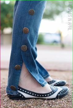 a person wearing black and white polka dot shoes with buttons on them, standing in front of a tree