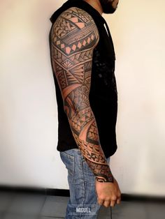 a man with a tattoo on his arm is standing in front of a white wall