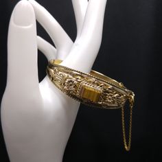 *Description: This is a beautiful gemstone hinged bracelet with safety chain from the 1940s to 1950s.  The bracelet has a layered design with filigree and then on top of this a rectangular gemstone in shades of brown.  It registers quartz on the Presidium gem tester.  The safety chain has a spring ring clasp so it may be attached or opened as designed. The bracelet clasp is a hidden box clasp and fit securely together.  This would be a great addition to your vintage jewelry collection or make a Vintage Bangle Jewelry For Wedding, Vintage Yellow Gold Cuff Bracelet With Intricate Design, Vintage Bangle For Wedding, Vintage Hinged Bracelets For Wedding, Vintage Hinged Bangle, Vintage Yellow Gold Hallmarked Cuff Bracelet, Vintage Yellow Gold Engraved Cuff Bracelet, Vintage Engraved Yellow Gold Cuff Bracelet, Gold Engraved Jewelry For Vintage Events