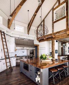 a large open concept kitchen and living room with wood floors, white walls and beams