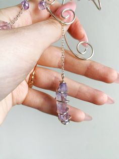 a woman's hand holding some kind of necklace with amethysts on it