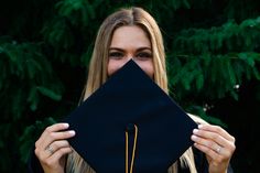 a woman holding up a graduation cap to her face