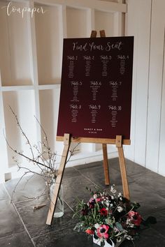 a table plan is set up on an easel with flowers in front of it