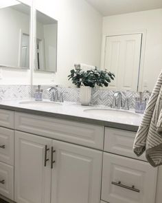 a bathroom with white cabinets and marble counter tops