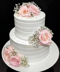 three tiered wedding cake decorated with pink roses and baby's breath pearls on a black background