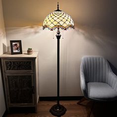 a lamp that is sitting on top of a table next to a chair and cabinet