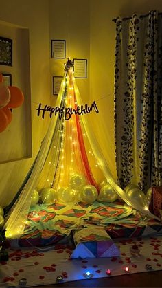 a birthday party with balloons and lights in the shape of a tent on top of a bed