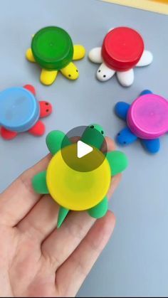 a person holding a small toy turtle in front of several other plastic toys on a table