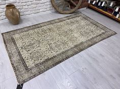 a large rug is on the floor in front of a brick wall and an antique wheel