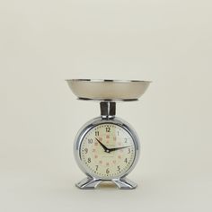 an alarm clock sitting on top of a silver plate with a bowl on the side