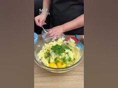 a woman is mixing food in a bowl with a spoon on the table next to her