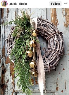 a wreath with bells and greenery hanging on the front door to an old wooden door