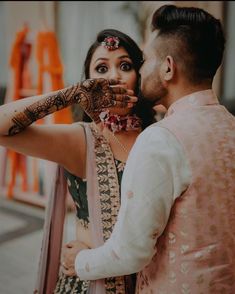 a bride and groom are posing for the camera while holding their hands up to their face