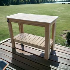 a small wooden table sitting on top of a wooden deck next to a green field