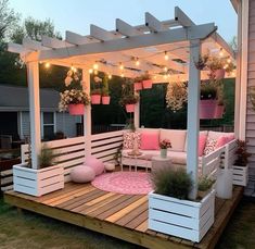 an outdoor patio with potted plants and lights on the roof, surrounded by wooden decking