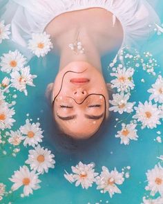 a woman floating in the water with daisies around her