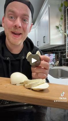 a man is holding an onion slice on a cutting board