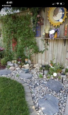 a small garden with rocks and plants in the back yard, next to a wooden fence