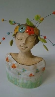 a ceramic head with various colored beads on it's face and hair in the shape of a woman