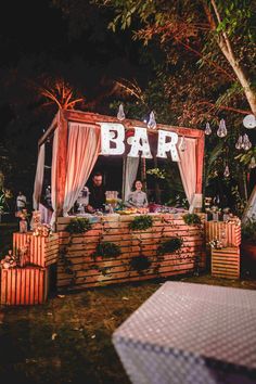 a bar set up in the middle of a field at night with people sitting around it