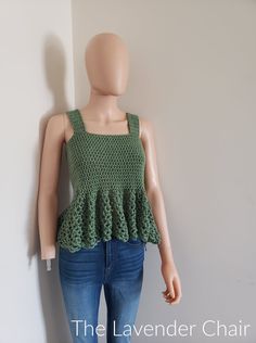 a female mannequin wearing a green crochet top and jeans, standing next to a white wall