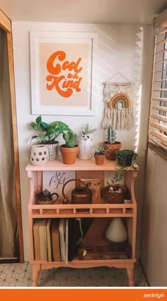 a pink shelf with books and plants on it in front of a white framed poster