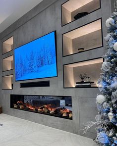 a large flat screen tv mounted to the side of a wall next to a christmas tree