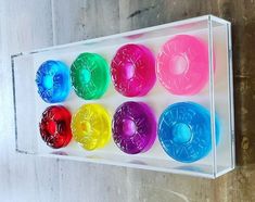 six different colored doughnuts are in a clear box on the wall next to each other