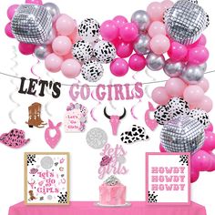 a pink table topped with balloons and decorations