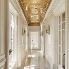 a long hallway with white walls and gold ceiling