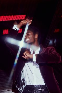 a man in a suit and tie holding his arms out to the side while standing next to a cross