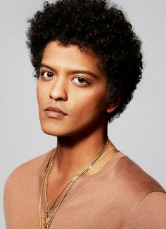 a close up of a person wearing a necklace and a sweater with an afro hairstyle