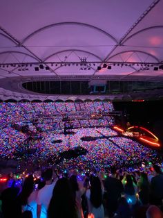 a large group of people standing in front of a stage with lights on the floor