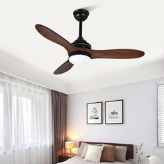 a bed room with a neatly made bed and a ceiling fan in the middle of it