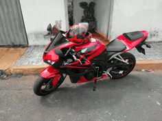 a red and black motorcycle parked in front of a building