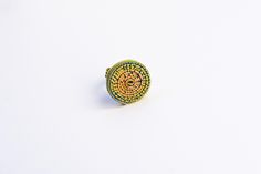 a yellow and green beaded ring sitting on top of a white surface