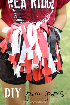 a girl in red shirt holding up a skirt made out of strips of duct tape