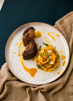 a white plate topped with food on top of a wooden table next to a brown cloth