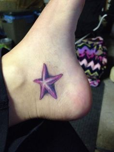 a small star tattoo on the foot of a woman's left leg, with pink and purple colors