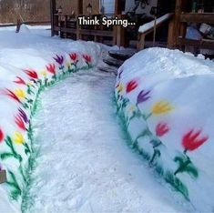 colorful flowers are painted on the snow in front of a house